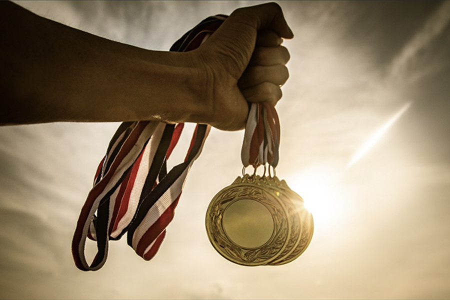 photo of a coach's hand holding all the gold medals